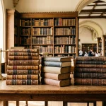 Stacks of classic theological volumes and religious books on solid wood library table in seminary library